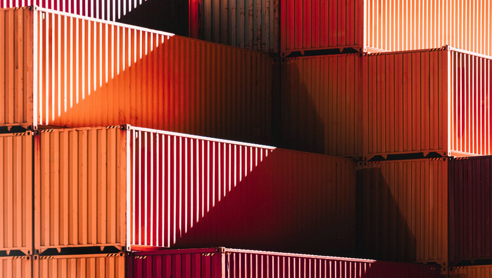 Stacked orange and red shipping containers in low sun
